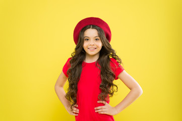Smiling child. Little girl with long hair. Kid happy cute face adorable curly hair yellow background. Lucky and beautiful. Beauty tips for tidy hair. Kid girl long healthy shiny hair wear red hat