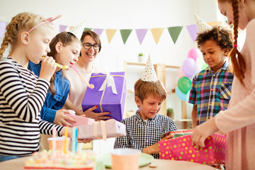 Portrait of happy  boy opening gifts from friends during Birthday party, copy space