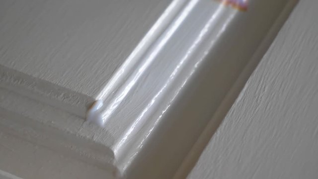 Refinishing a cabinet door with white paint - close up.