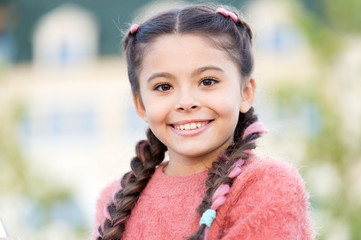 Beauty is the smile of a child. Beauty look of adorable small girl outdoor. Little child with cute smile on beauty face. Happy beauty girl with long braided hair smiling on summer day