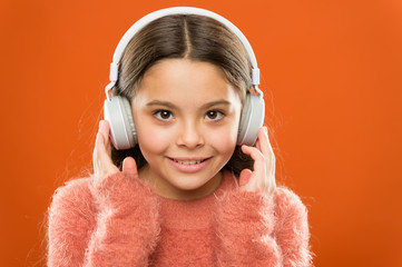 Modern music is her life style and pleasure. Little modern girl wearing bluetooth headphones. Small child listening to music in everyday life. Using modern technology in daily life. Modern life