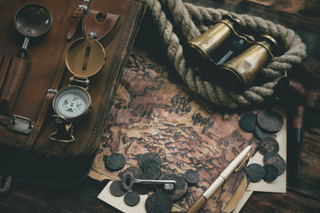 Treasure map and adventurer accessories on a wooden table background. Treasure hunt concept...