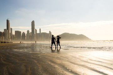 couple walking on the beach of Balne&aacute;rio Cambori&uacute; (Brazil)