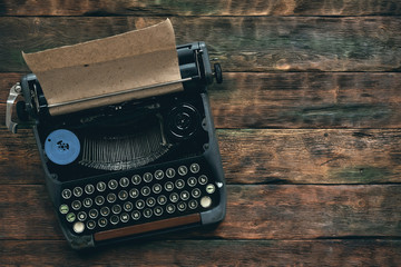 Old typewriter on a writer wooden desk flat lay background with copy space.