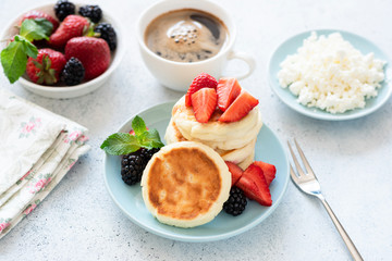 Cottage cheese pancakes Syrniki with strawberries and cup of coffee on table. Russian, Ukrainian cuisine
