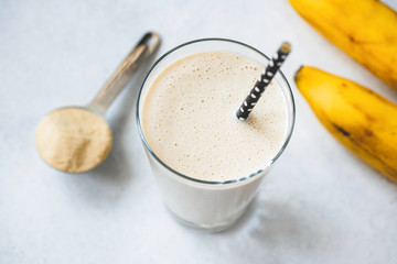 Vegan protein banana shake or smoothie in glass. Top view, selective focus - obrazy, fototapety, plakaty
