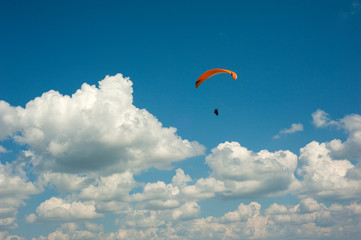 One paraglider is flying in the blue sky against the background of clouds. Paragliding in the sky on a sunny day.