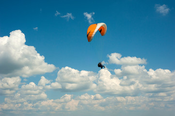 One paraglider is flying in the blue sky against the background of clouds. Paragliding in the sky on a sunny day.