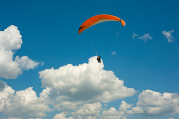 One paraglider is flying in the blue sky against the background of clouds. Paragliding in the sky on a sunny day.