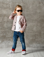 Image of cheerful excited little boy child standing isolated over concrete wall.