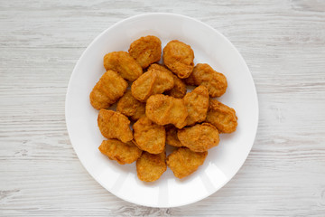 Chicken nuggets on a plate on a white wooden background, top view. Overhead, from above, flat lay. Close-up.
