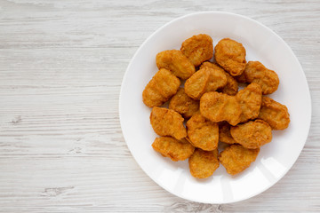 Chicken nuggets on a plate on a white wooden background, top view. Overhead, from above, flat lay. Copy space.