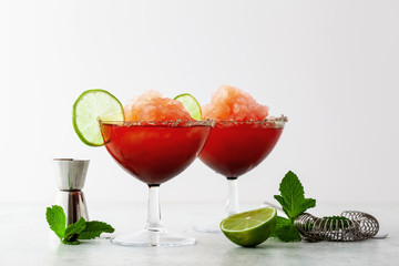Red Frozen Margarita, refreshing cocktail on the table and lime with mint