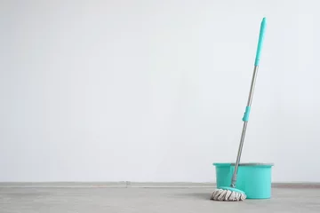 Fotobehang Bucket with a mop on a floor on a white wall background with copy space. Wet cleaning concept background. © Dmitriy