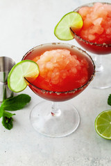 Red Frozen Margarita, refreshing cocktail on the table and lime with mint