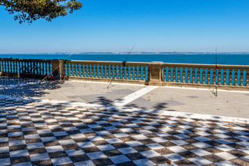 Three fishing rods at the oceanfront promenade of Alameda Apodaca Park in Cadiz, Province of Cadiz, Andalusia, Spain