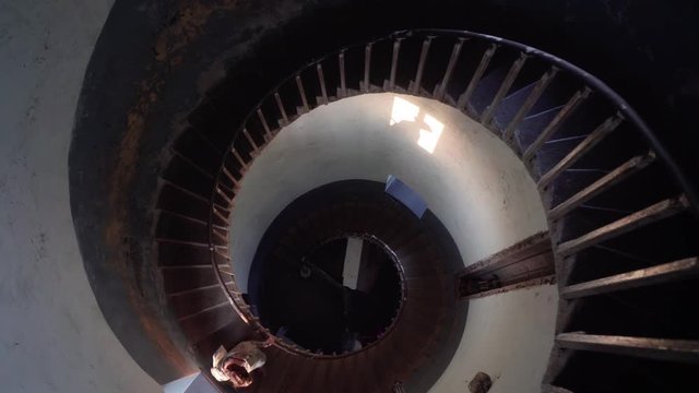 Interior top down view inside lighthouse staircase in Mamallapuram, India. Female making her way down abstract diminishing stairs.
