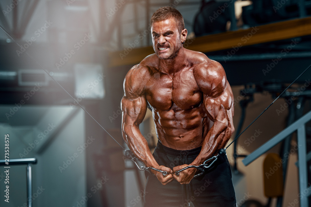 Wall mural body builder workout at the gym. performing cross over exercise for chest muscles