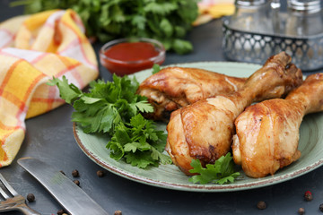 Chicken drumsticks, baked in a marinade of ketchup, soy sauce and balsamic vinegar on a plate on a dark background
