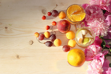 Colorful flowers of pink peony on a wooden table, summer drinks and different fruits, top view with copy space, selective focus. Pink flowers and dietary fruits and juices on a wooden background,