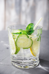 Detox cucumber, lemon and mint cocktail on cement table, vertical view