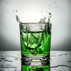 The splashes from the falling ice in green cocktail