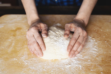 Close-up of female hands holding a ball of dough cooking at home
