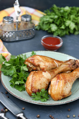 Chicken drumsticks, baked in a marinade of ketchup, soy sauce and balsamic vinegar on a plate on a dark background
