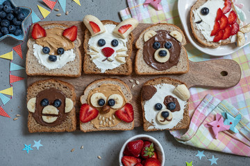 Funny animal faces toasts with spreads, banana, strawberry and blueberry