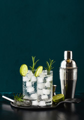 classic gin and tonic cocktail with rosemary sprigs in tall glasses on a table with bar accessories - obrazy, fototapety, plakaty