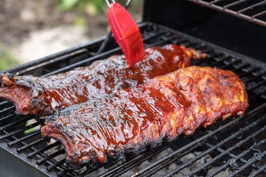 Pork ribs cooking on barbecue grill for summer outdoor party.