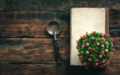 Book and a magnifying glass on a wooden table background with copy space.