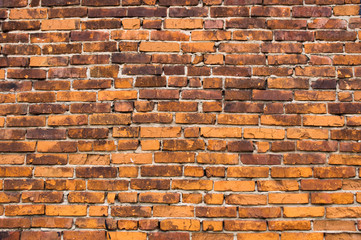 Background of old brick wall. The old orange-brown cracked brick, uneven rows