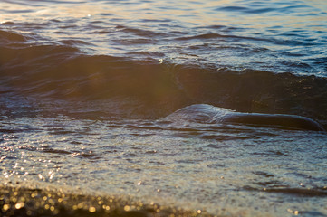 pebble stones on the sea beach, the rolling waves of the sea with foam