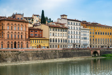 Fototapeta na wymiar Colorful buildings line the banks of the Arno River in Florence, Italy.