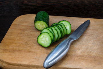 Steel knife and sliced ​​cucumber on a cutting board for healthy food.