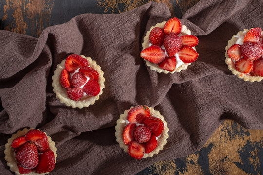 Tartlets with fresh strawberry on dark rustic background, top view