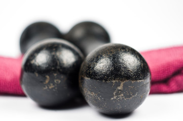 Two vintage cast iron black weights stacked on a pink towel on white background closeup