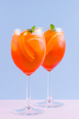 Cocktail Aperol Spritz on a blue pink background. Italian cocktail aperol spritz in pop art style. Summer trendy drink on pastel background