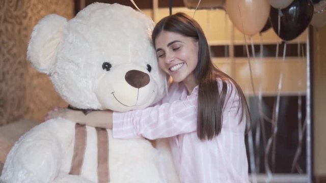 Young lady hugging a huge teddy bear with joy, medium shot