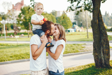 Fototapeta premium Family in a summer park. Mother in a white t-shirt. Cute little boy with a dad