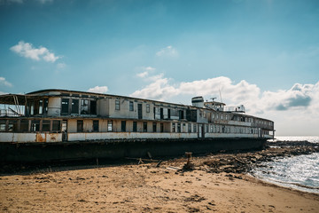 Old abandoned rusted ship aground after shipwreck accident in coast on sand beach