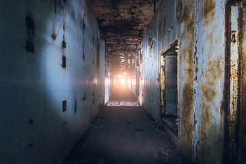 Creepy corridor in abandoned nuclear power plant with light in end