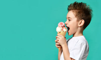 Baby boy kid hold three scoops of strawberry and vanilla ice cream in waffles cone on blue mint background - Powered by Adobe