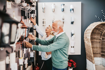 Senior couple in home lighting store shoosing shandelier for their home