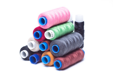 Spools of thread laid horizontally on top of each other on white background