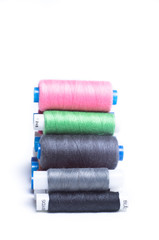 Spools of thread laid horizontally on top of each other on white background