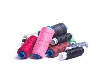 Colored spools of thread are a bunch on white background