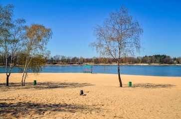 Beautiful spring landscape. Empty beach by the lake on a sunny day.