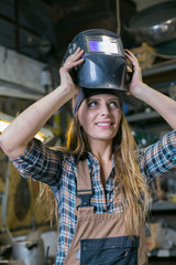woman in workshop putting on welding mask